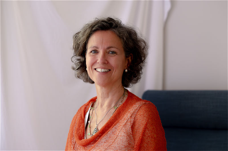 Retrato de Olga Muñoz sonriendo, con jersey naranja